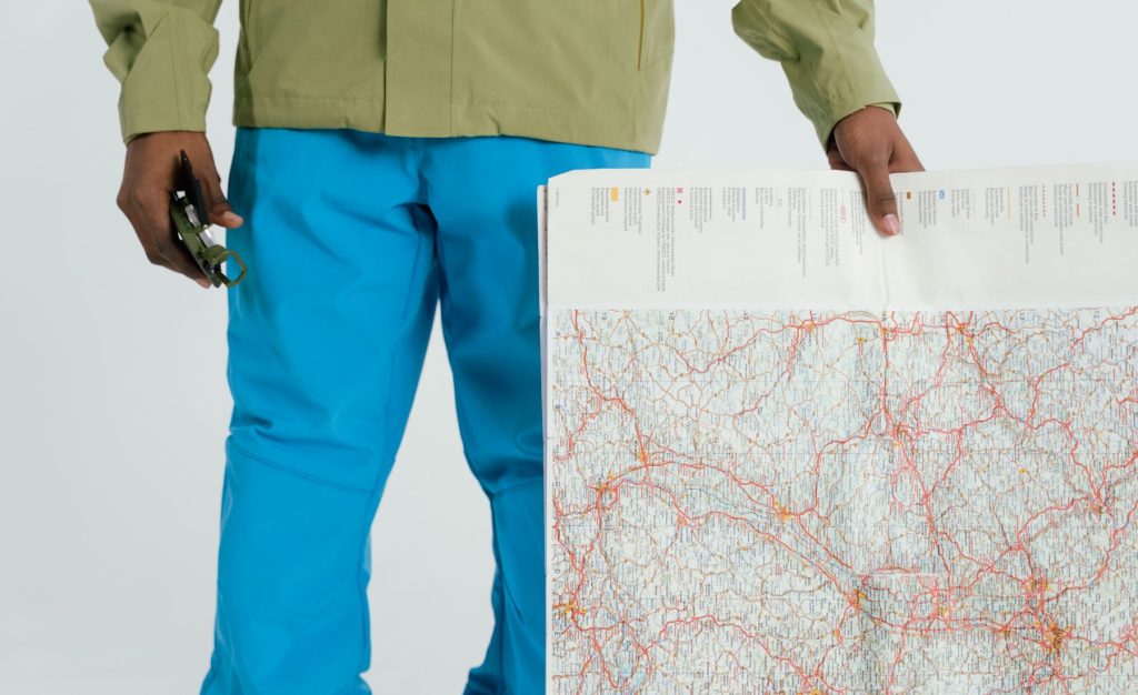 Person holding a map and compass while planning an outdoor route.