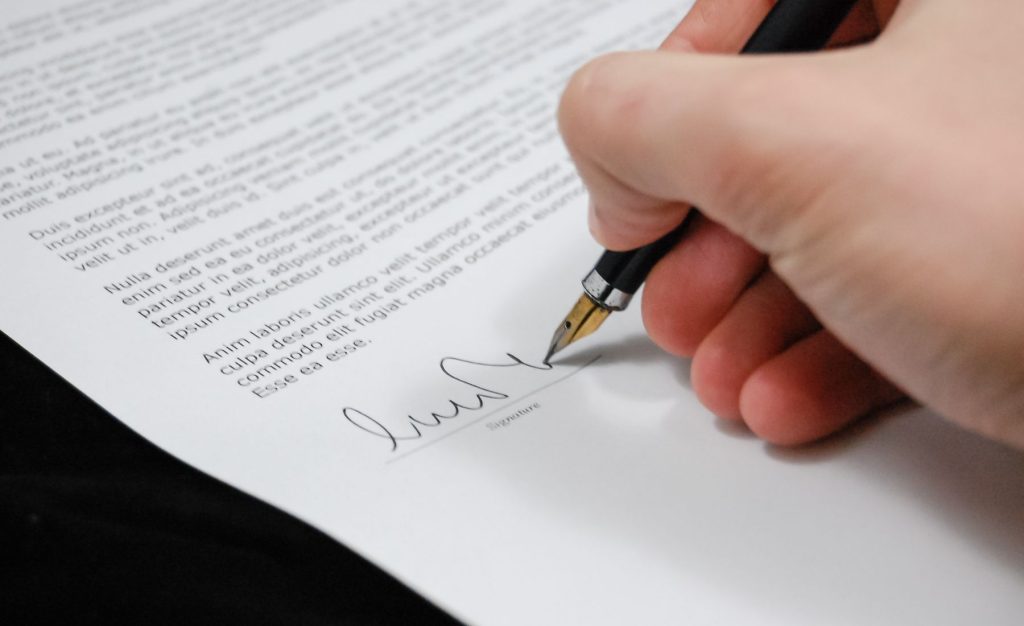 Hand signing an agreement with a fountain pen.